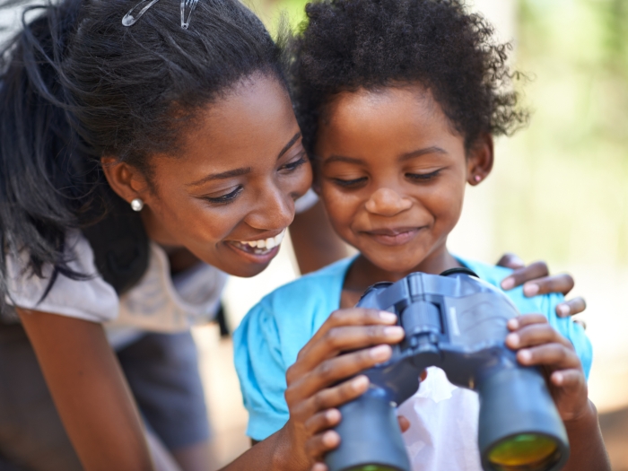 Woman and child smiling holding binoculars